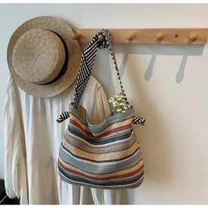 Detail of colorful woven tote bag with black and white striped straps and knot accents