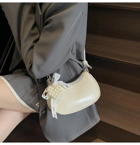 Detail of off-white leather dumpling bag featuring heart pearl lace pendant