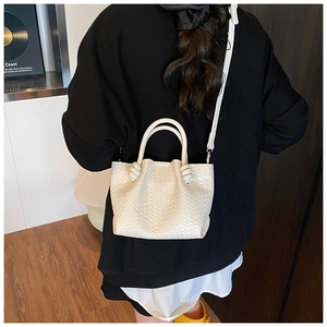Detail of cream woven leather bucket bag with unique knot handle and crossbody strap