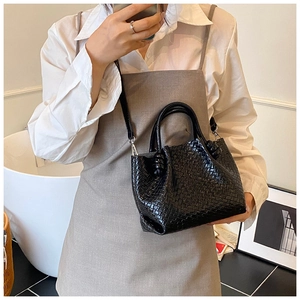 Detail of black woven leather bucket bag with silver metal hardware and knotted side accents