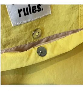 Detailed macro view of yellow nylon bag with silver magnetic clasp and rules label