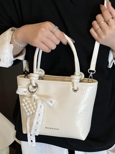 Sac seau chic en cuir verni beige avec poignée nouée et breloque coeur en perle