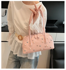 Close-up of pink leather shoulder bag with silver star studs and white faux pearls