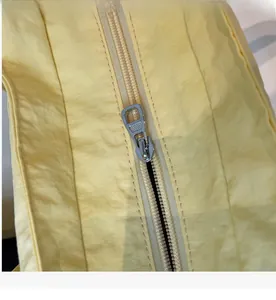 Detailed close-up of the smooth silver metal zipper on a yellow canvas tote bag
