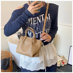 Detail of beige woven bucket bag showing the intricate checkerboard texture and drawstring