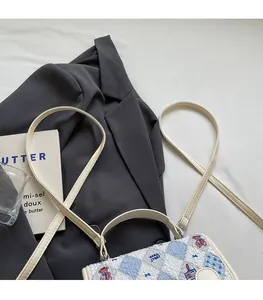 Gros plan d'un sac à dos blanc matelassé avec des motifs d'ours et sangle réglable