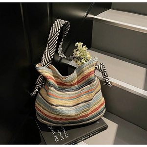 Detail of colorful striped woven beach bag with black and white patterned fabric strap