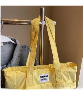 Close-up of vibrant yellow canvas tote bag with black lettered fabric patch detail