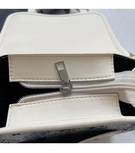 Détail de la fermeture éclair en métal argenté sur le sac à dos en similicuir ivoire