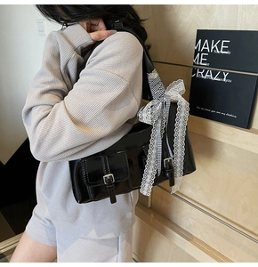 Dettaglio della borsa tote nera con fiocco in pizzo e fibbie argentate sulle tasche