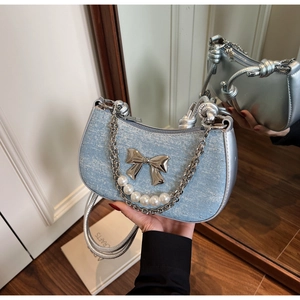 Detail view of denim crescent bag featuring rhinestone embellishments and a metal bow