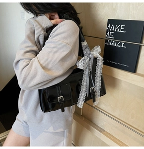 Vista dettagliata della borsa tote nera con fiocco in pizzo e tasche con fibbia