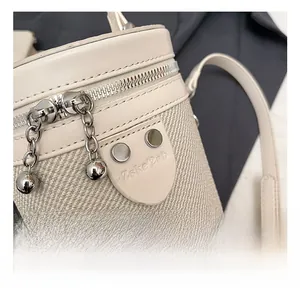 Dettaglio della borsa a secchiello beige con cerniera in metallo argento e pendente a sfera
