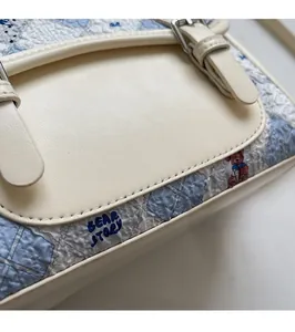 Gros plan du sac à dos matelassé crème avec motif à carreaux bleus et coutures fines