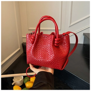 Detail of red woven leather bucket bag featuring distinctive knots and luxury texture