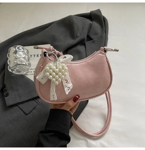 Detail of pink dumpling bag with pleated texture, lace bow and pearl heart charm