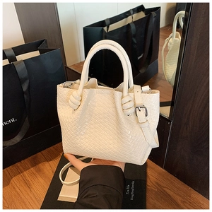 Detail view of white woven bucket bag with knotted handles and adjustable strap