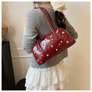 Detail of red patent leather shoulder bag with star rivets and pearl decorations