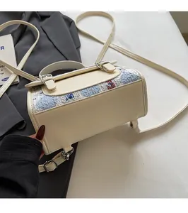 Détail du sac à dos en similicuir crème avec tissu matelassé bleu et motif d'ours