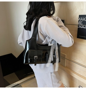 Dettaglio della borsa hobo in vernice nera con nastro di pizzo bianco su una modella