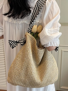 Handwoven straw tote bag with black and white striped straps for summer beach vacations