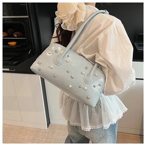 Detail of light blue leather shoulder bag with star rivets and pearls in a kitchen setting