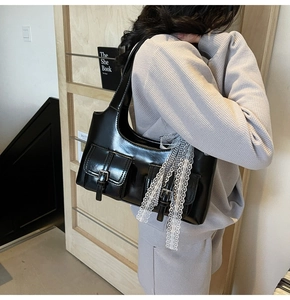 Vista dettagliata della borsa tote nera lucida con tasche a fibbia e nastro di pizzo