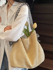 Handwoven straw tote bag with black and white striped straps and bow for summer beach travel