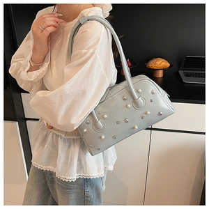 Detail of light blue leather shoulder bag with decorative pearls and silver metallic studs