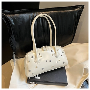 Detail of cream white leather bag with metallic star studs and faux pearl accents