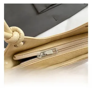 Nahaufnahme des Metall-Reißverschlusses und der cremefarbenen Faltenleder-Handtasche