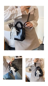 Detail view of black patent leather bucket bag with white lace pearl bow accessory