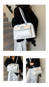 Detail view of white tote bag featuring blue trim and front pocket with emblem