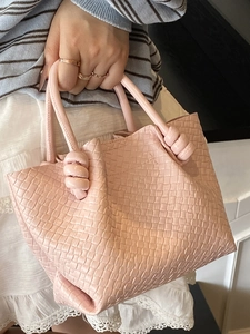 Chic pink woven bucket bag with knotted handle for women in a stylish casual summer setting
