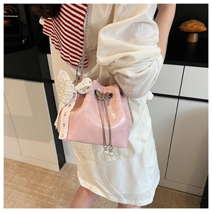 Sac seau en cuir verni rose avec nœuds en dentelle blanche et détails de fleurs en perles