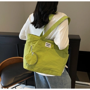 Neon green large nylon tote bag with mini coin purse shown on female model shoulder