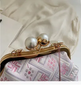 Close-up of golden metal frame with large pearl clasps on embroidered cheongsam handbag