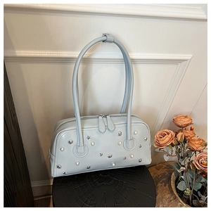 Detail view of light blue glossy leather bag with pearl, star, and sun metal rivets