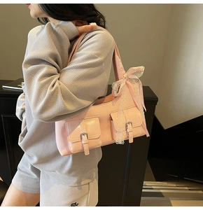 Dettaglio della borsa tote in ecopelle rosa con tasche a fibbia e ciondolo a fiocco