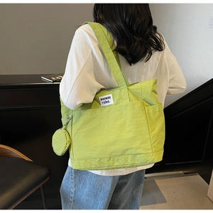 Close-up of neon green nylon tote bag with brand label and matching mini coin purse detail