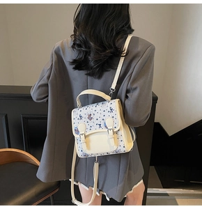 Mini sac à dos crème avec rabat en tweed bleu et broderie ours porté par un mannequin