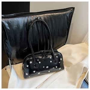 Detail of glossy black patent leather handbag with silver star and pearl decorations