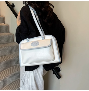 Detail view of pearlescent white shoulder bag with light blue trim and brand logo