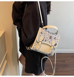 Détail d'un sac à bandoulière crème imprimé ours avec un pull en maille gaufrée café