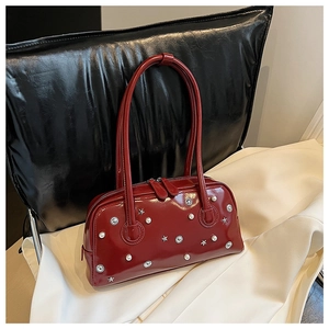 Detail of burgundy patent leather shoulder bag with vintage star studs and pearl accents