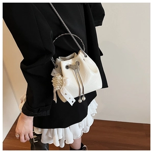 Détail d'un mini sac seau blanc avec breloques en perles et fermoir papillon métallique