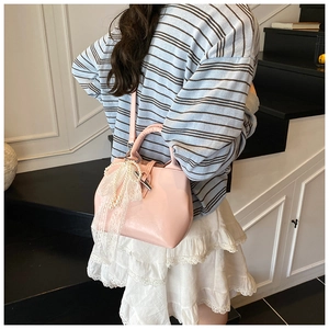 Detail of light pink bucket bag with pearl lace bow charm on a model in a stair setting