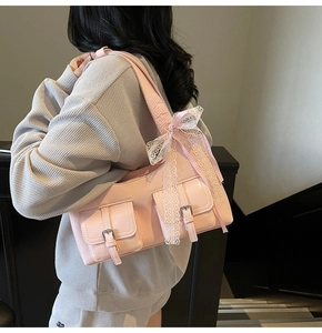 Dettaglio borsa sottobraccio in pelle rosa con fiocco di pizzo e tasche con fibbia