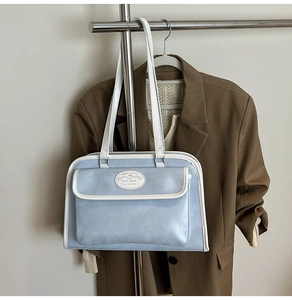 Detail of light blue and white shoulder bag with dual straps and front pocket