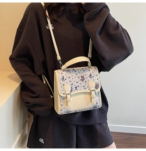 Détail du sac blanc crème avec imprimé ours, nœud bleu et boucle métallique rétro